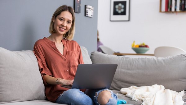 Otthonról dolgozva egy laptopon a kanapéról Otthonról dolgozva egy laptopon a kanapéról